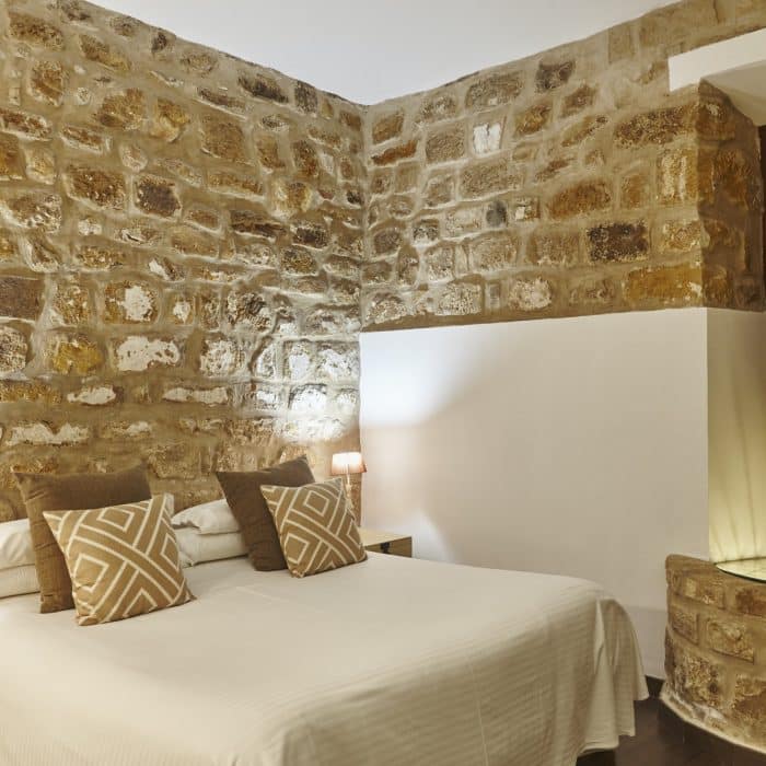 bedroom-with-stone-walls-comfortable-modern-hotel-room-interior-architecture.jpg